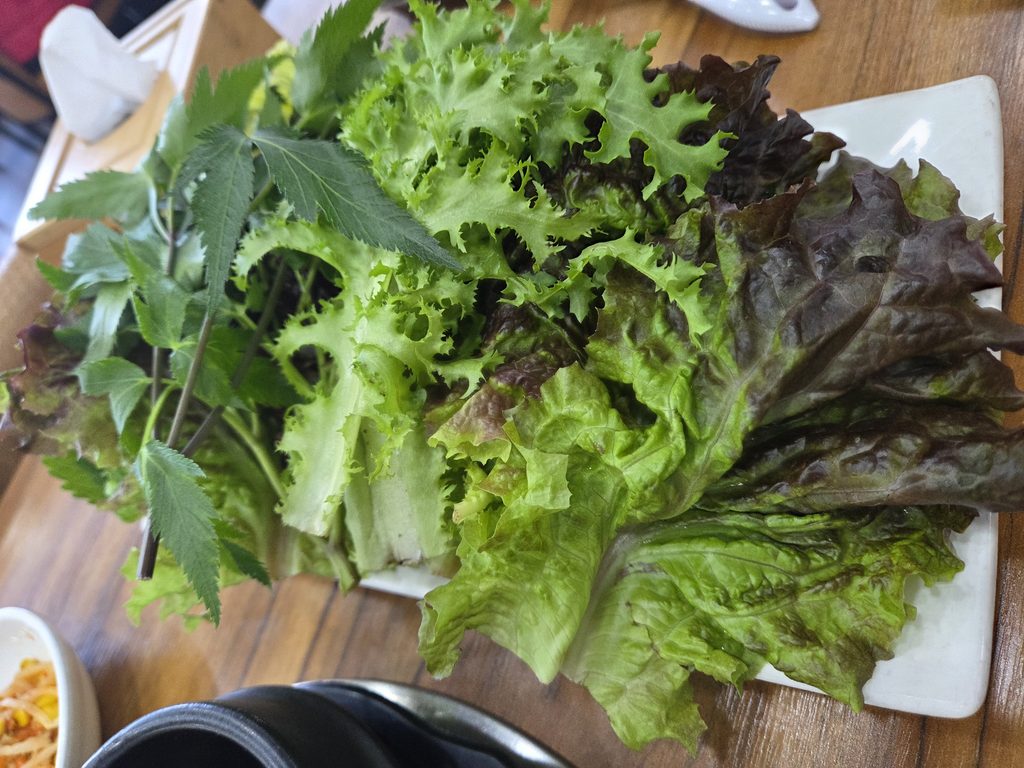 인천 가정동 똑순이네 우렁쌈밥에서 제공하는 신선한 쌈 채소. 상추, 깻잎, 당귀 등 다양한 채소가 담긴 모습.