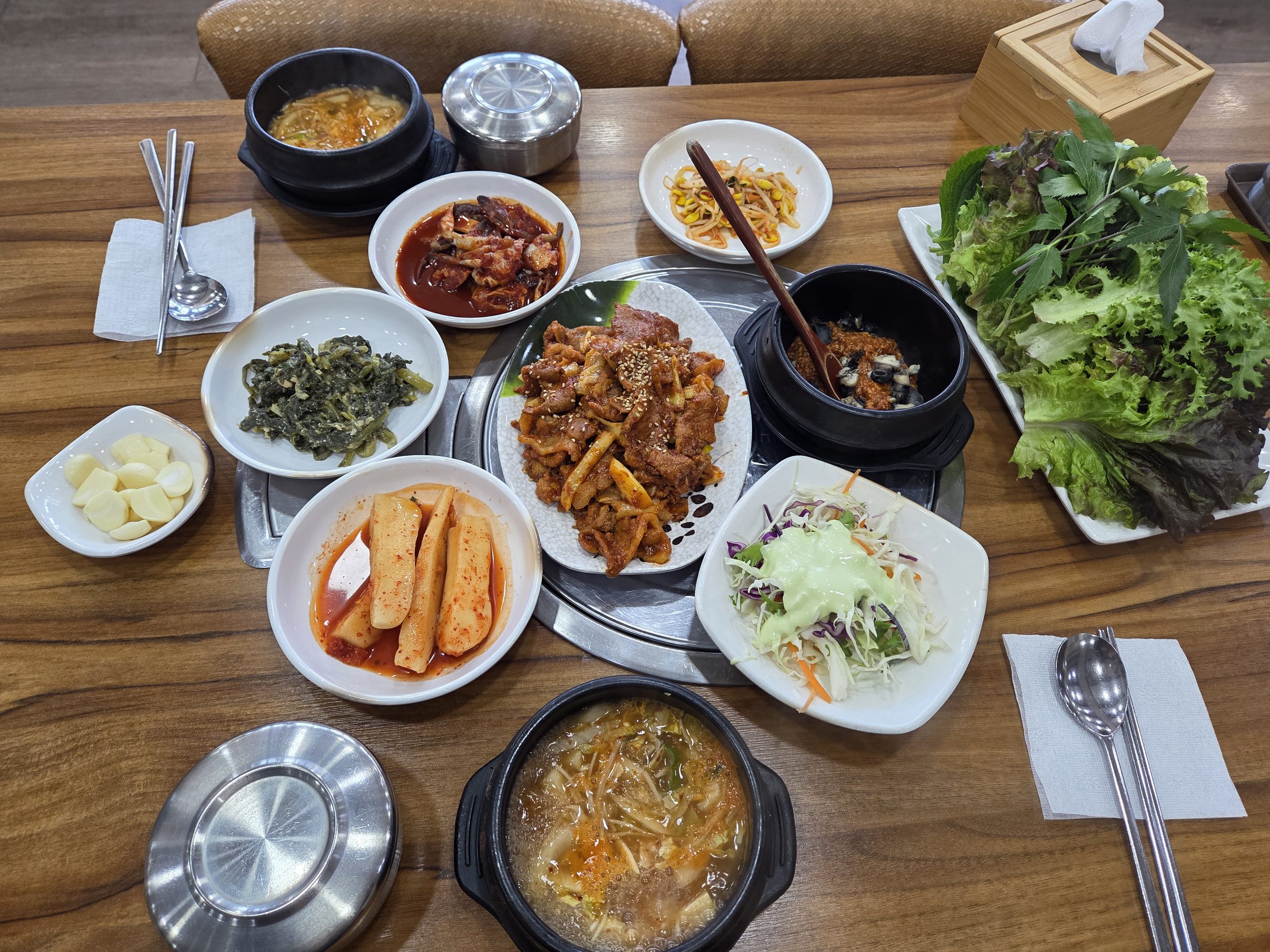 인천 가정동 똑순이네 우렁쌈밥의 제육쌈밥 한 상. 제육볶음, 우렁쌈장, 된장찌개, 흑미밥과 다양한 쌈 채소 및 밑반찬이 차려진 모습.