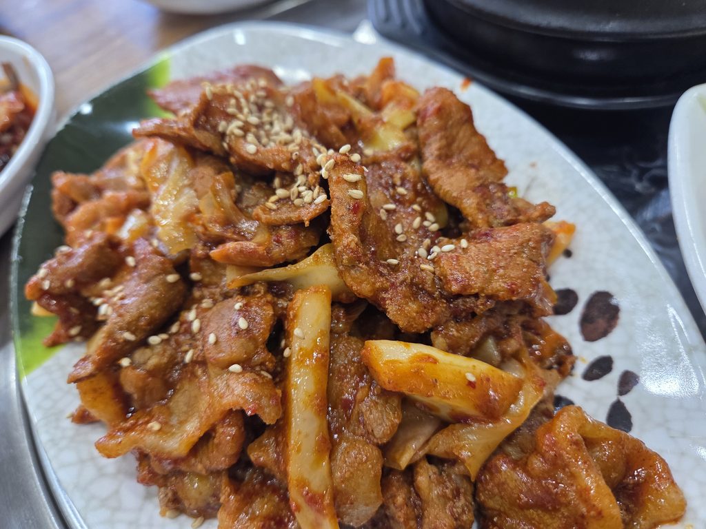 인천 가정동 똑순이네 우렁쌈밥의 제육볶음. 양념에 볶아낸 돼지고기에 깨가 뿌려져 있는 모습.